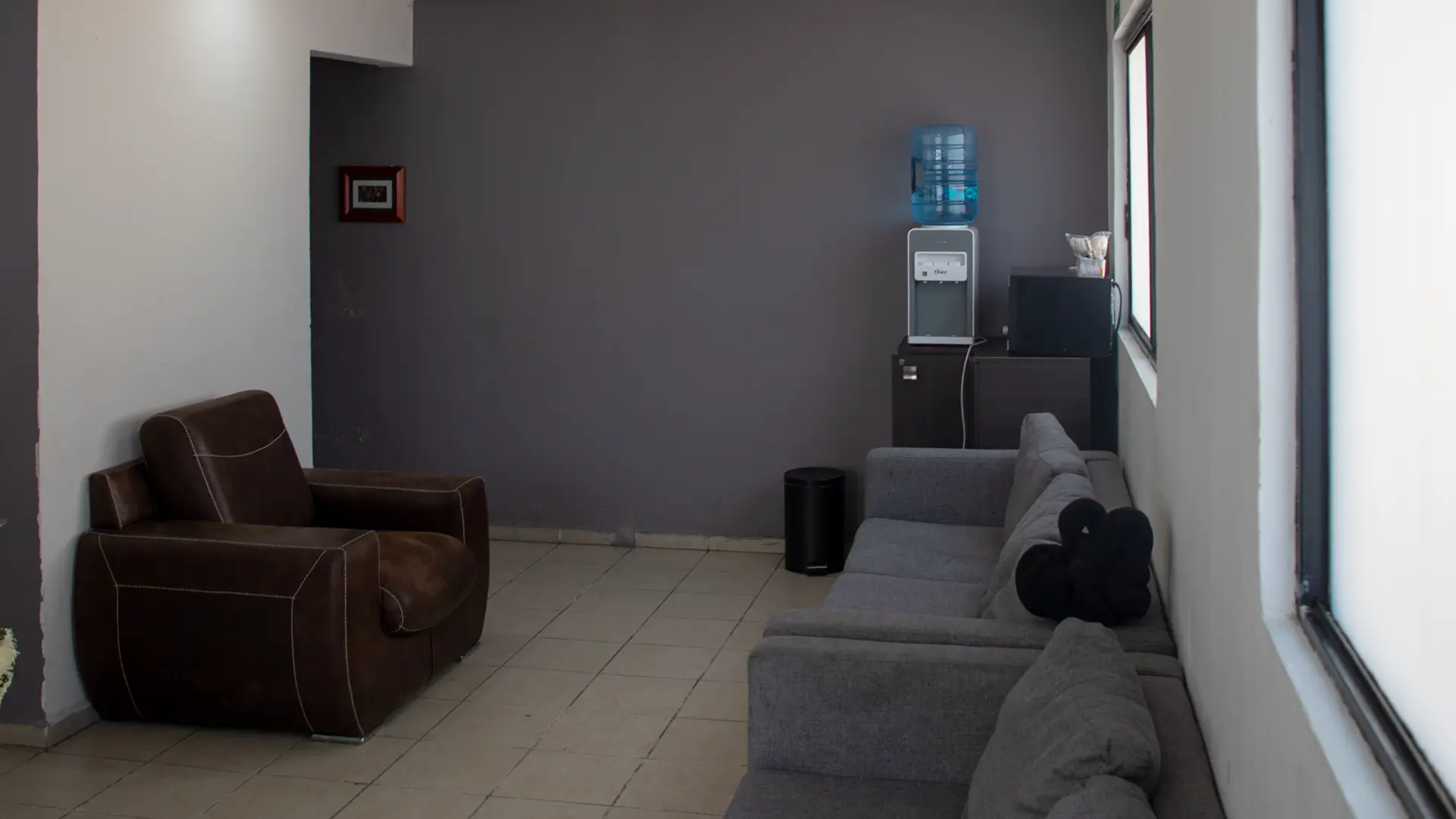 Área lateral de la sala con sillones, sofá y servicio de agua