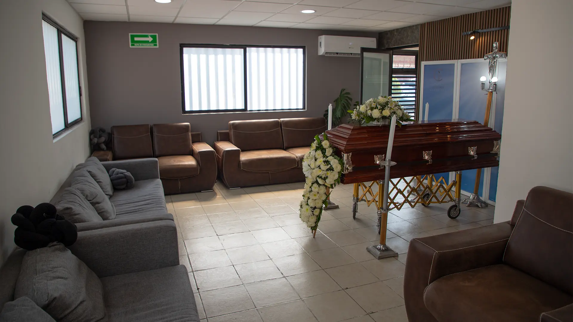 Sala de velación preparada con ataúd, flores y área de estancia